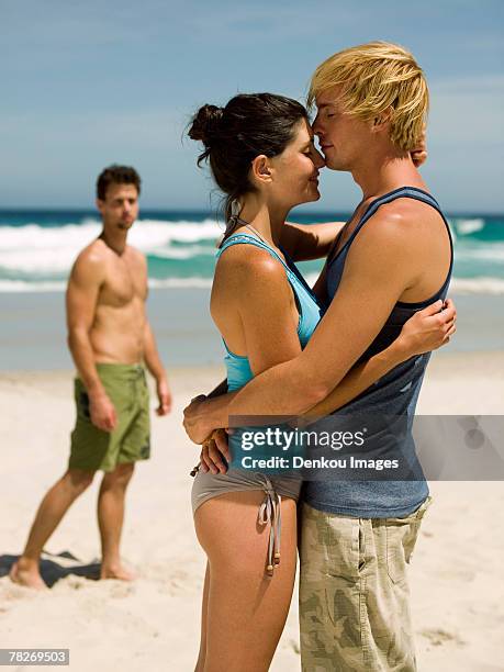 couple hugging, another man in the background. - swimwear singlet stock pictures, royalty-free photos & images