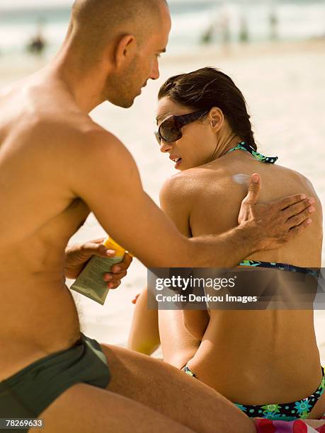 man applying suntan lotion on his girlfriend. - suntan lotion stock-fotos und bilder