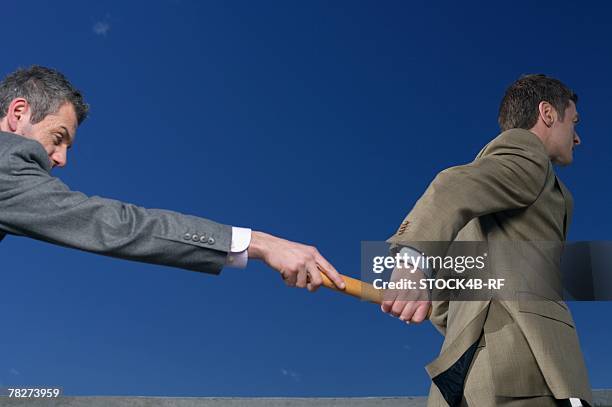 businessman passing baton to colleague - rf business stock pictures, royalty-free photos & images