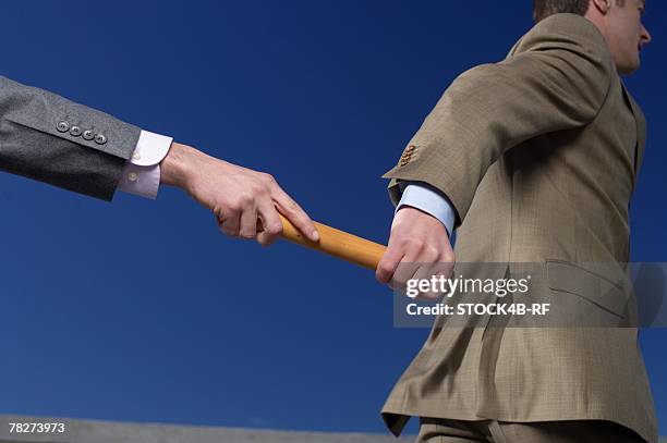 businessman passing baton to colleague - relais athlétisme mains photos et images de collection