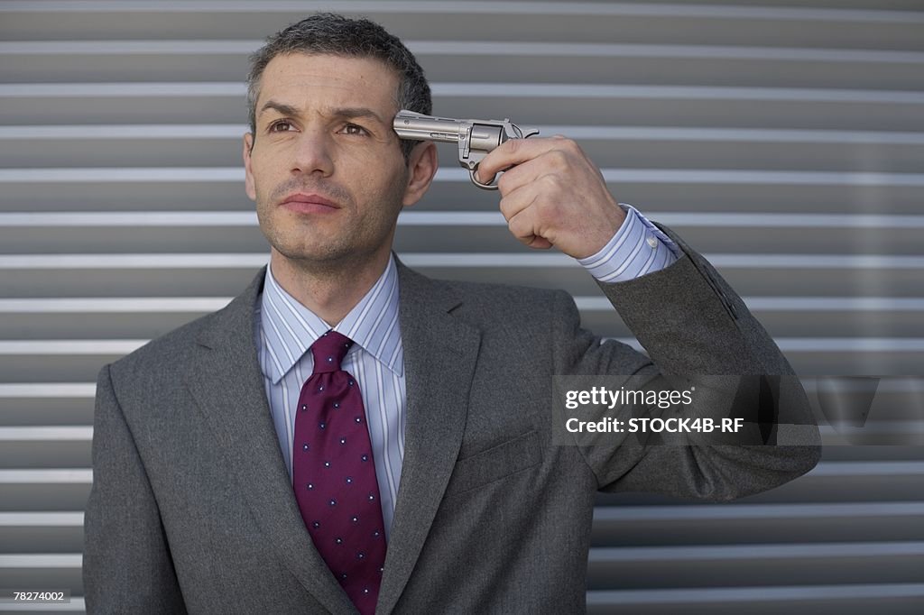 Businessman holding a gun to head