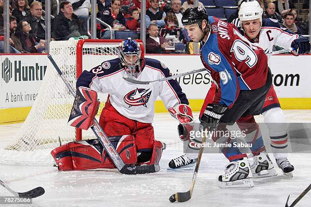 Goaltender Pascal Leclaire of the Columbus Blue Jackets keeps his eyes on the puck as Ryan Smyth of the Colorado Avalanche skates with the puck in...