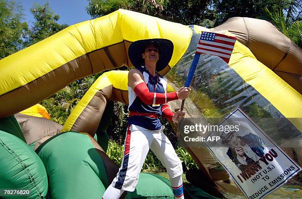 An environmental activist acts of cutting down an inflated plastic tree during a demonstration at the venue of the UN Climate Change Conference 2007...