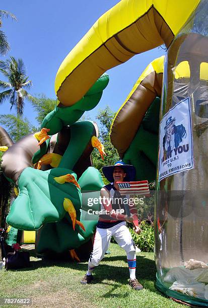 An environmental activist acts of cutting down an inflated plastic tree during the demonstration at the venue of the UN Climate Change Conference...