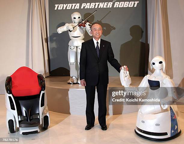 President of Toyota Motor Corp, Katsuaki Watanabe poses with the company's new partner robot Mobility Robot "Mobina and a violin playing robot ,...