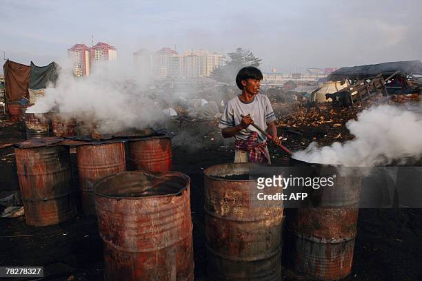 Smoke rises from a worker burning coconut husks to be used as charcoal, in Jakarta, 06 December 2007. The US environmental group, the National...