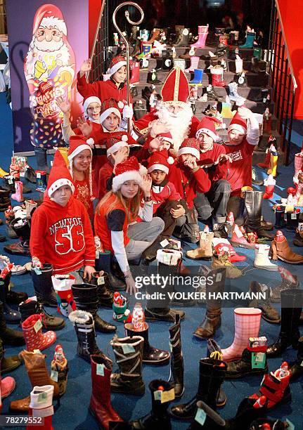Man disguised as Santa Claus and children pose amid of Santa boots filled with candies 06 December 2007 at the "Theater am Marientor" theatre in...