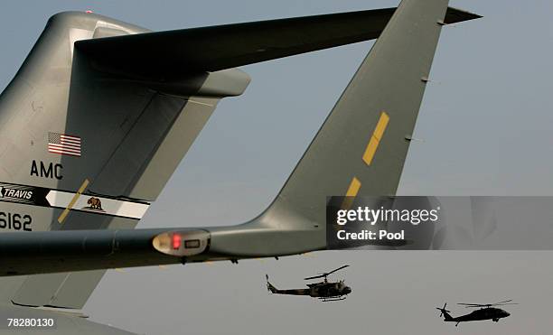 An Iraqi military helicopter, left, and a U.S. Army Blackhawk helicopter fly near a U.S. Air Force transport plane preparing to transport U.S....