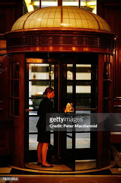 Worker cleans the revolving doors in the main entrance lobby of The Savoy hotel on December 6, 2007 in London. Some of the fixtures and fittings are...