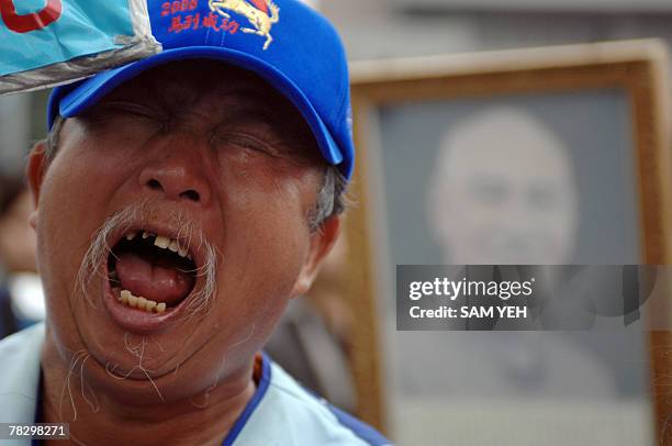 Veteran cries next to a photo of late president Chiang Kai-shek in front of the main gate of the CKS Memorial Hall in Taipei, 07 December 2007....