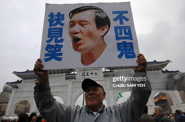 Government supporter displays a photo of opposition presidential candidate Ma Ying-jeou in front of the main gate of the CKS Memorial Hall in Taipei...