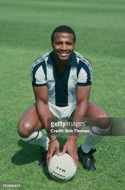 English professional footballer Cyrille Regis of West Bromwich Albion posed with a football on the pitch, circa 1980.