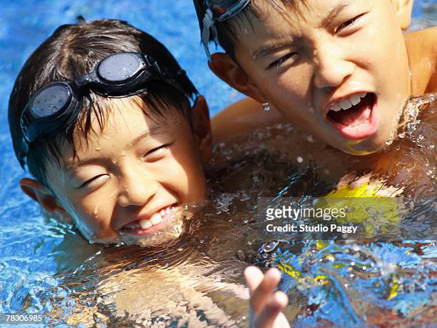 close-up of two boys swimming in a swimming pool - singapore pool stock pictures, royalty-free photos & images