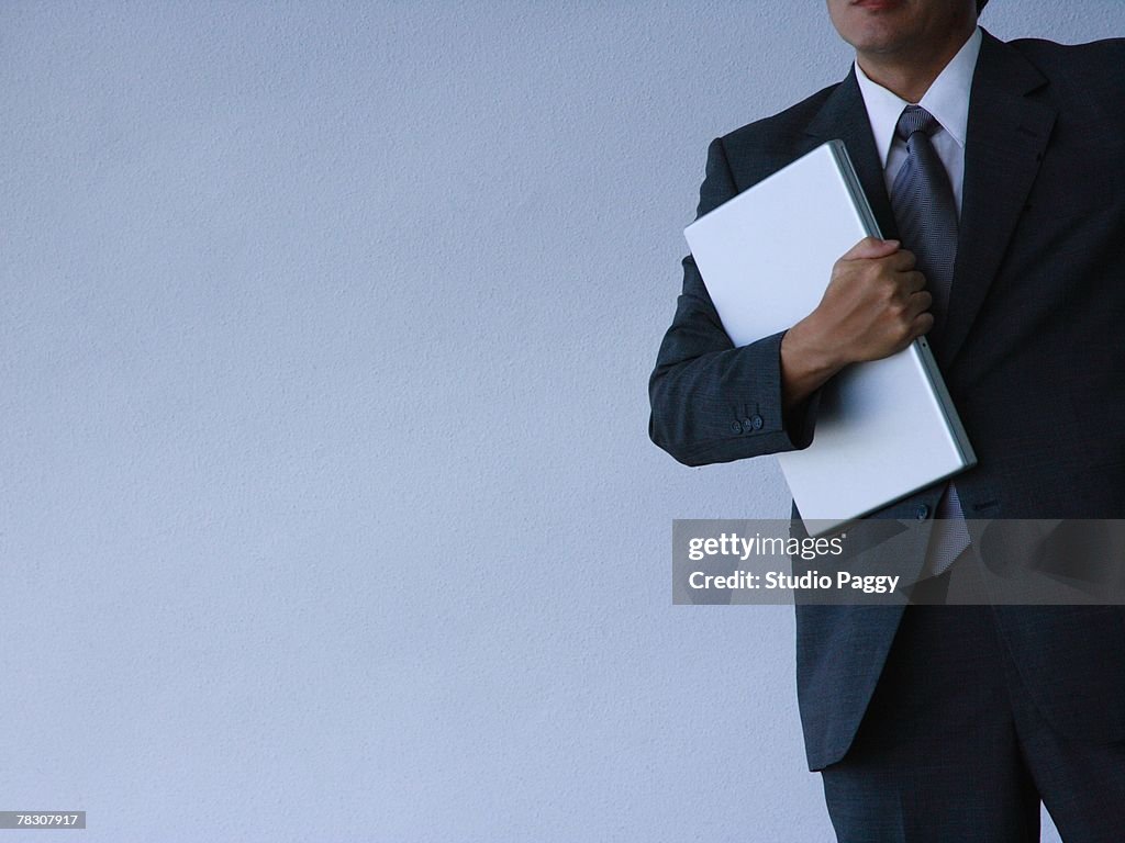 Mid section view of a businessman carrying a laptop