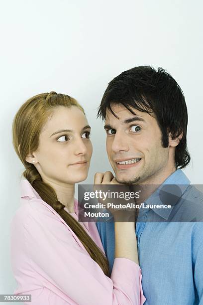 young couple together, man making faces at camera, woman looking at man - cheesy grin stock pictures, royalty-free photos & images