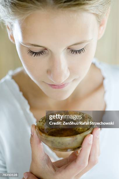 woman holding up small bowl to nose, close-up - essence day stock pictures, royalty-free photos & images