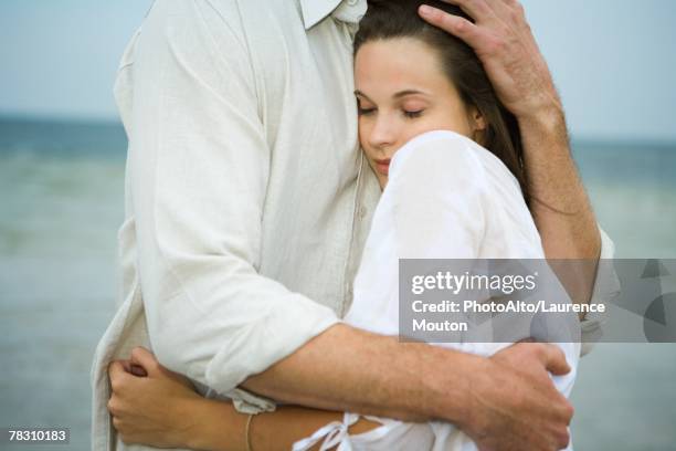 man and young female companion embracing, close-up - beschützer stock-fotos und bilder