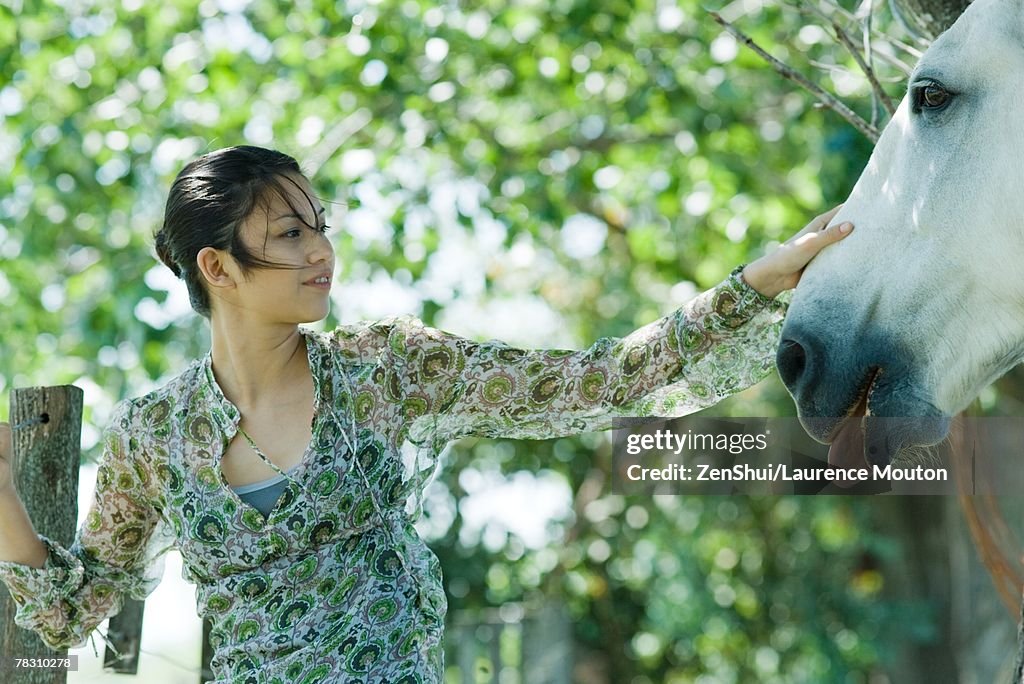 Young woman touching horse
