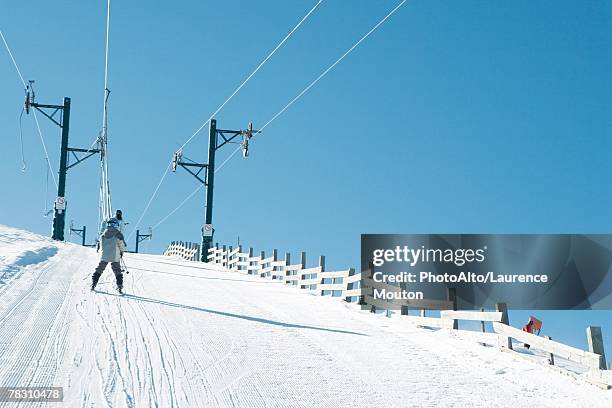 young skier going up hill on ski lift, rear view - tellerlift stock-fotos und bilder