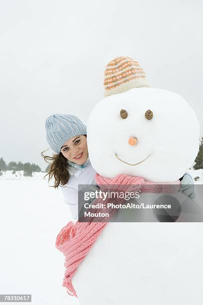 female embracing snowman, smiling at camera, portrait - frau schneemann stock-fotos und bilder