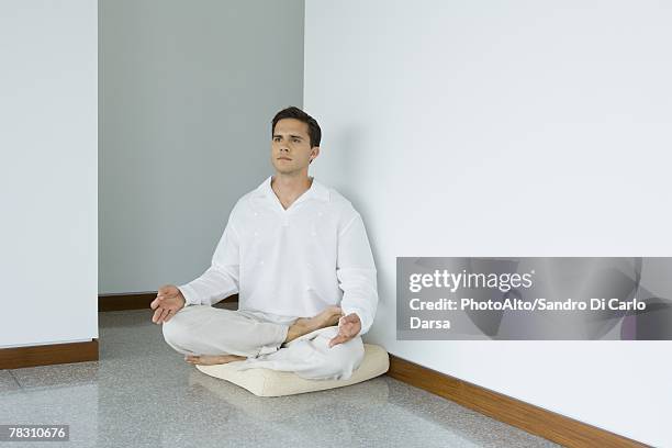 man sitting in lotus position on cushion, looking away - 胡坐　横 ストックフォトと画像