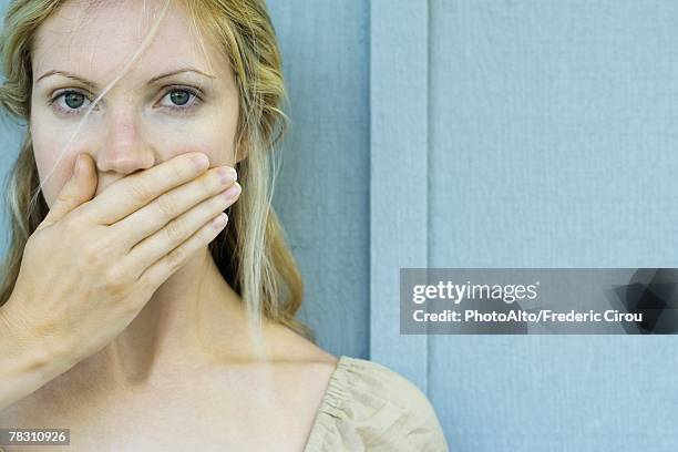 woman covering mouth with hand, looking at camera - mão na boca imagens e fotografias de stock