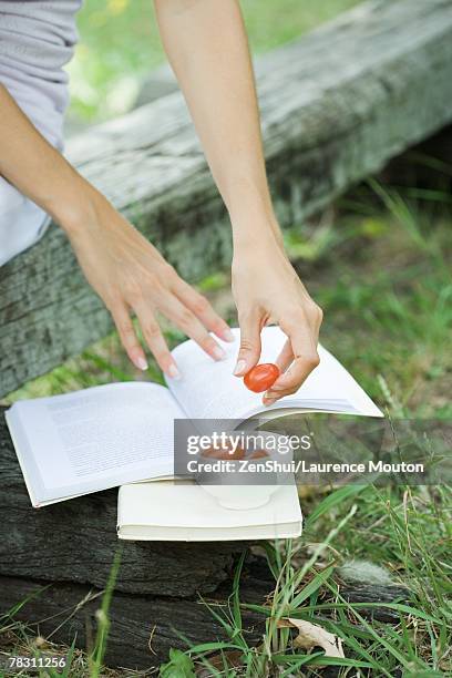 woman reading book and eating cherry tomatoes, cropped - arm made of vegetables stock pictures, royalty-free photos & images