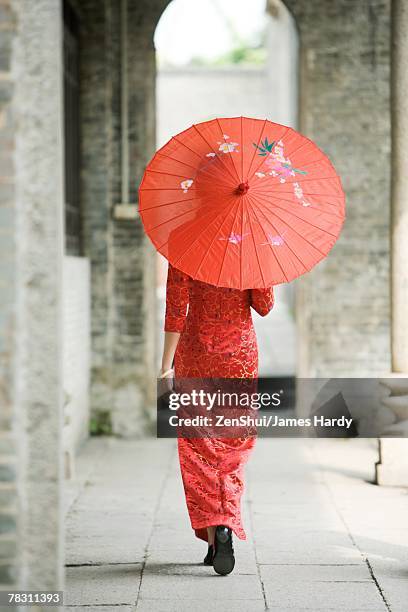 young woman dressed in traditional chinese clothing walking with parasol, rear view - papierschirm stock-fotos und bilder