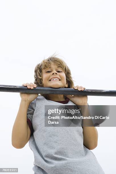 boy doing pull-up, chin resting on bar, smiling at camera - boys in pullups stockfoto's en -beelden