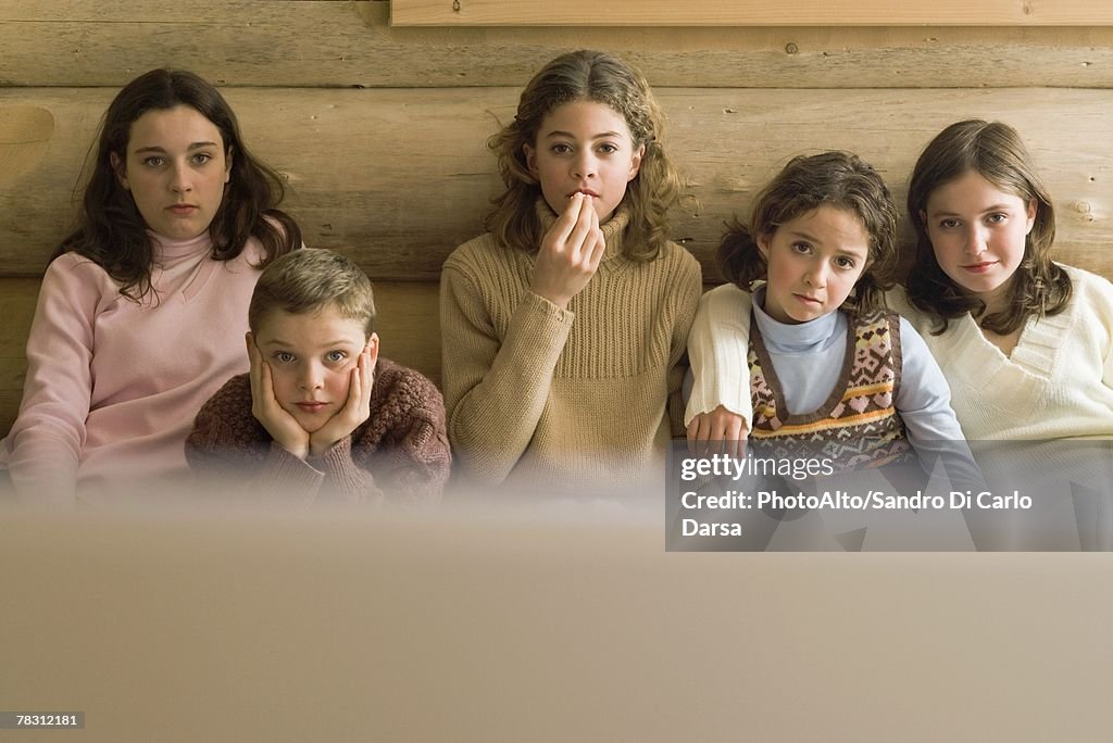 Group of teen and preteen friends and siblings watching TV, front view