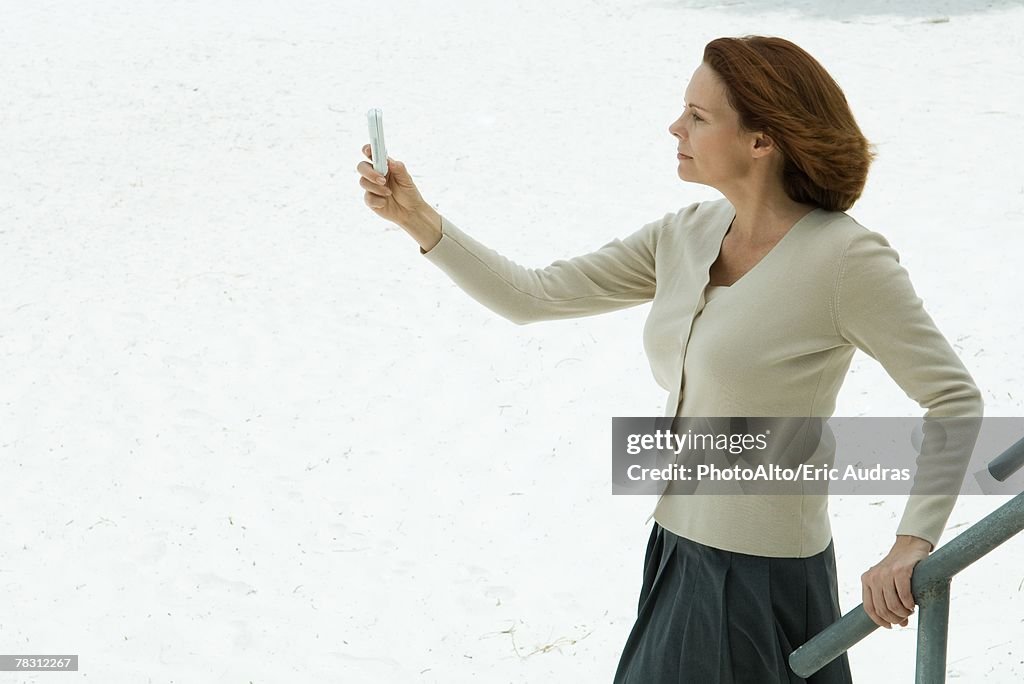 Woman looking at cell phone, arm outstretched, side view