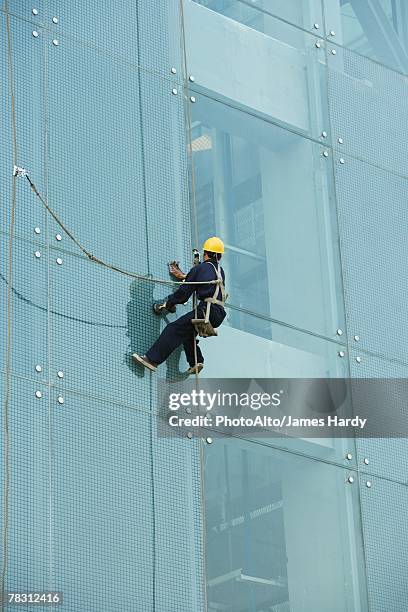 window washer on side of office building, close-up - descente en rappel photos et images de collection