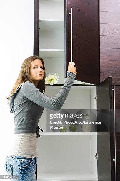 teen girl opening pantry, looking at camera - open day 14 stock pictures, royalty-free photos & images