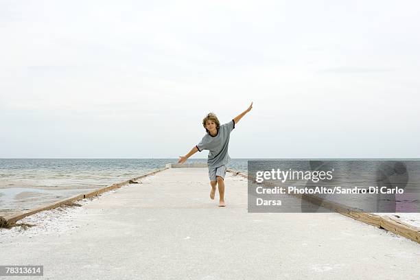 boy running at the beach with arms outstretched, front view - 飛行機のまね ストックフォトと画像