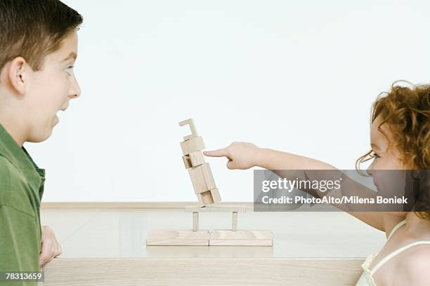 little girl knocking over blocks while brother watches in surprise - northern european descent ストックフォトと画像