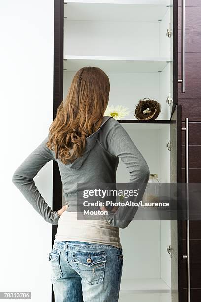 teen girl standing in front of sparse pantry with hands on hips, rear view - open day 14 stock pictures, royalty-free photos & images