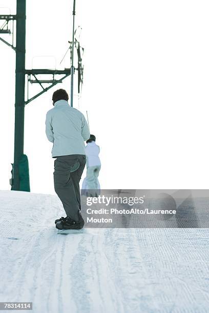 snowboarder going up hill on ski lift, rear view - tellerlift stock-fotos und bilder