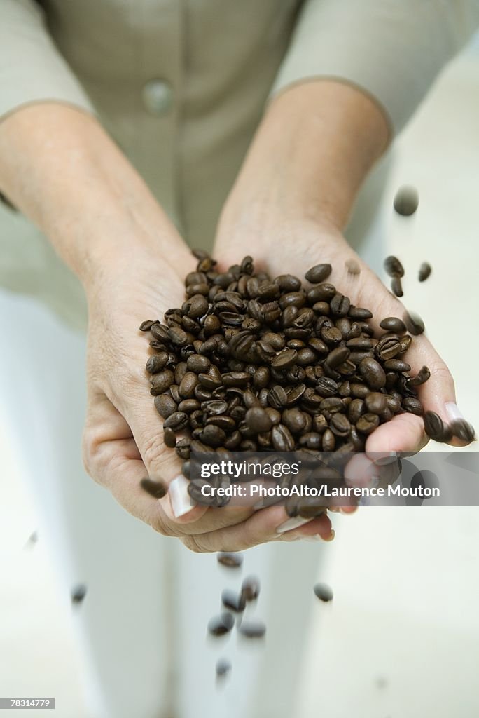 Woman's hands holding coffee beans, cropped