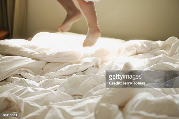feet of child jumping on bed - piumone foto e immagini stock