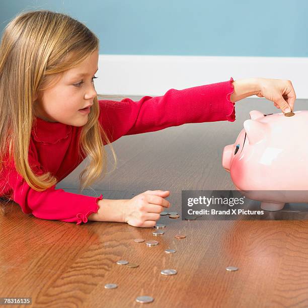 girl putting coins in piggy bank - blonde girl piggy bank stock-fotos und bilder