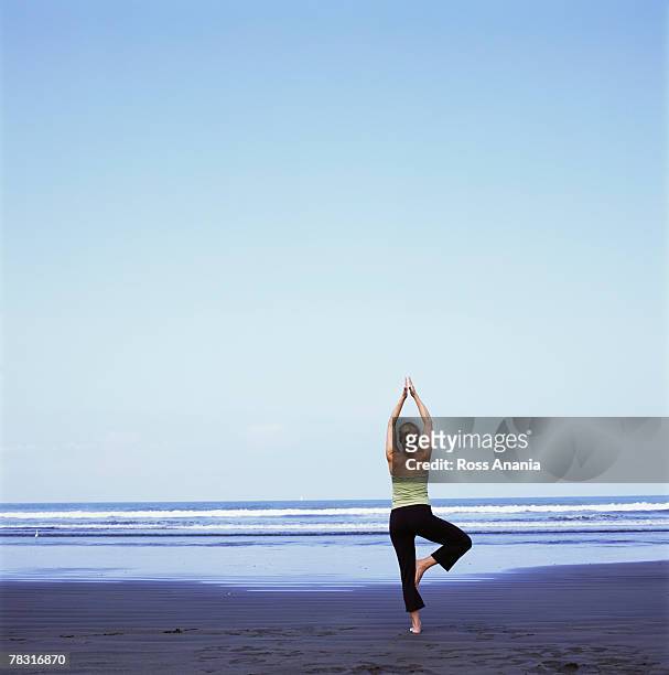 woman in yoga pose on beach - halber lotussitz stock-fotos und bilder