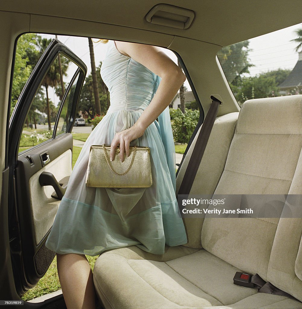 Teenage girl in dress getting out of car