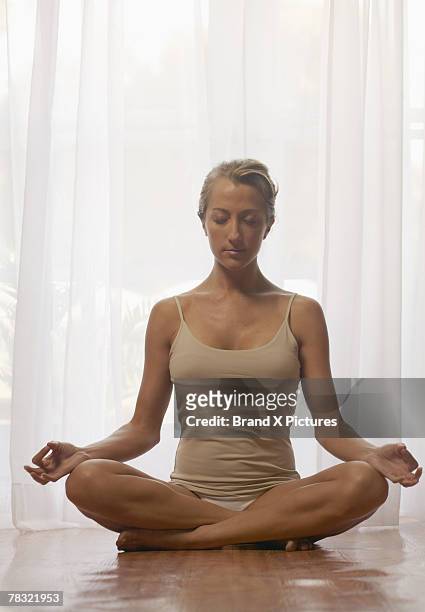 woman doing yoga indoors - halber lotussitz stock-fotos und bilder