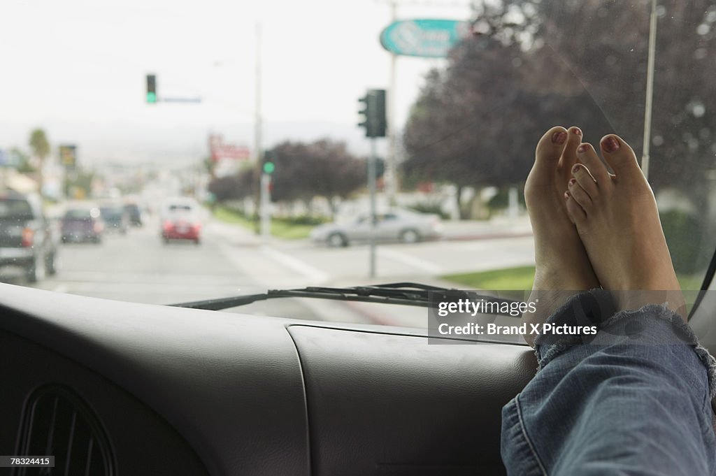 Bare feet on dashboard of car