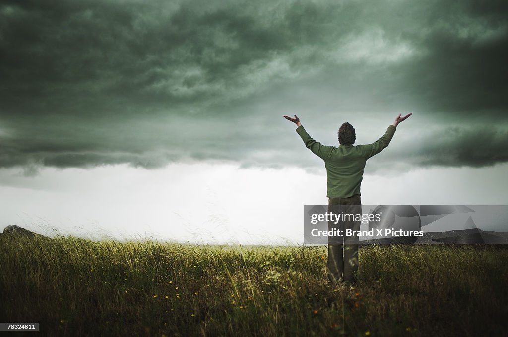 Person in field with arms raised