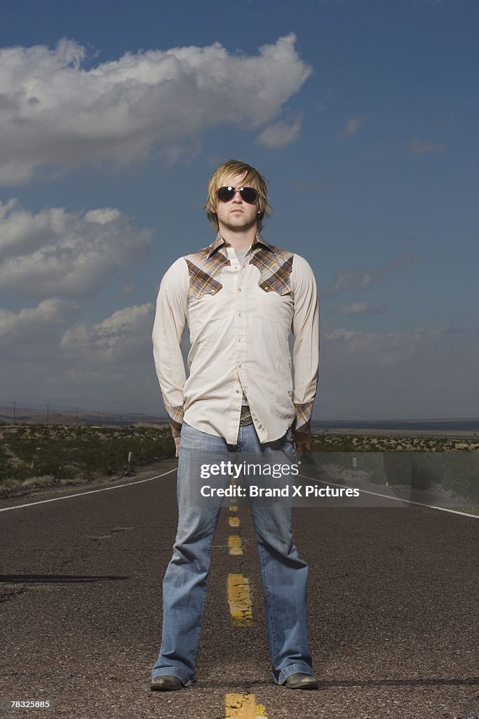 Confident man standing in middle of desert road