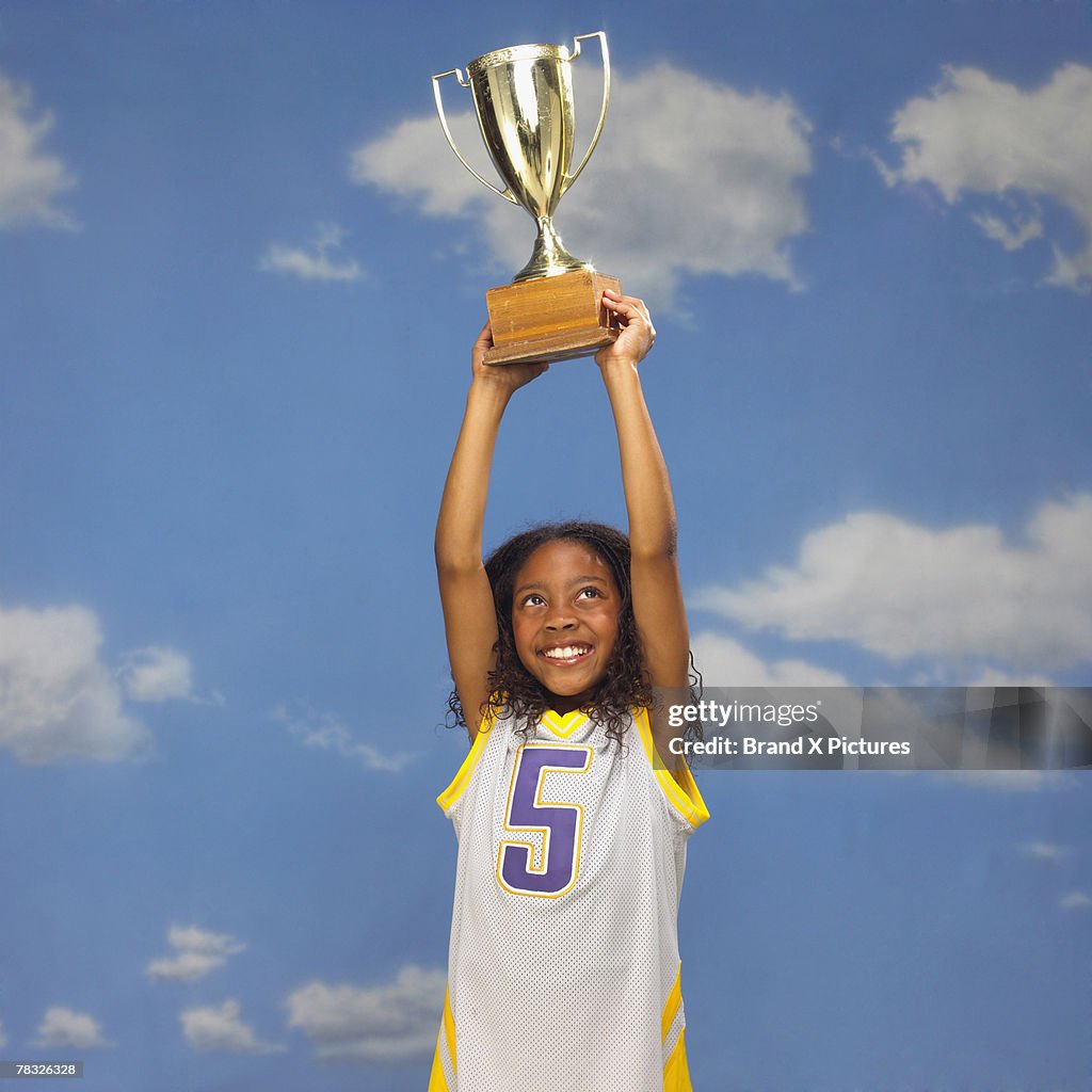 Basketball player holding trophy overhead