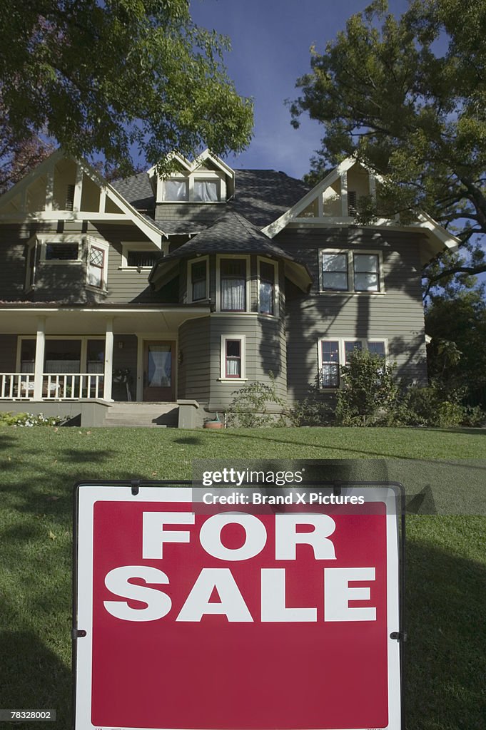 For Sale sign in front yard of house