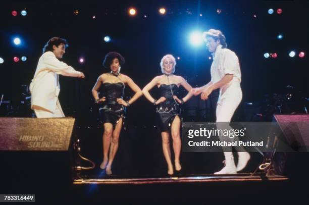 Andrew Ridgeley and George Michael of Wham! performing during the pop duo's 1985 world tour in January 1985. In the background are backing singers...