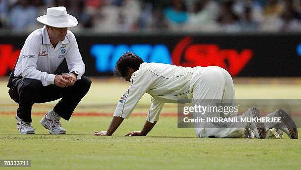 Umpire Simon Taufel watches as Pakistani cricketer Shoaib Akhtar rests on the ground after suffering from cramps on the first day of the third Test...